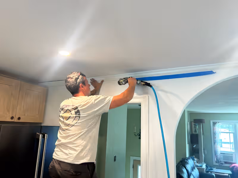 Empirical Renovations carpenter nailing crown moulding above a kitchen doorway in Vermont