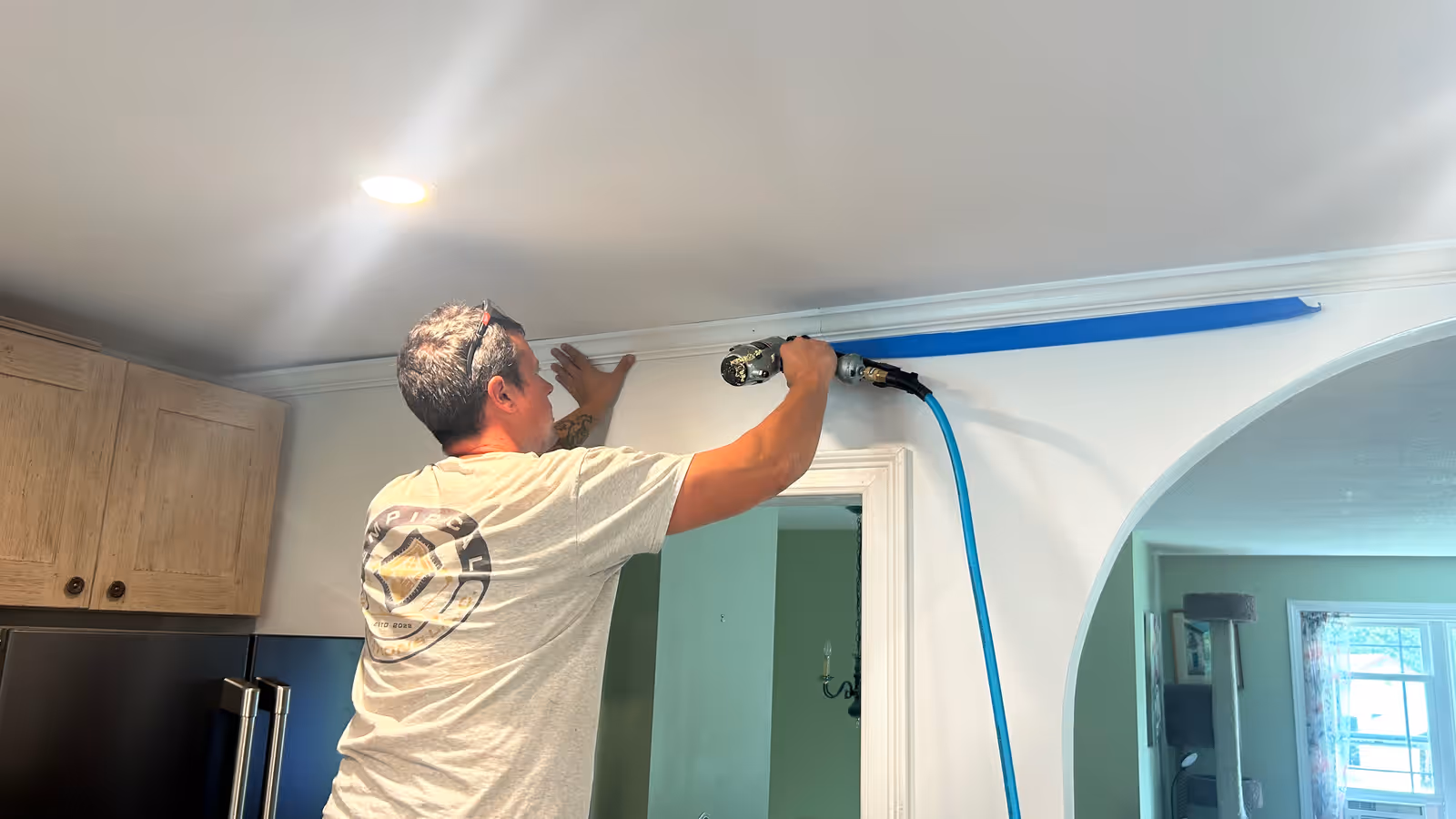 Empirical Renovations carpenter nailing crown moulding above a kitchen doorway in Vermont