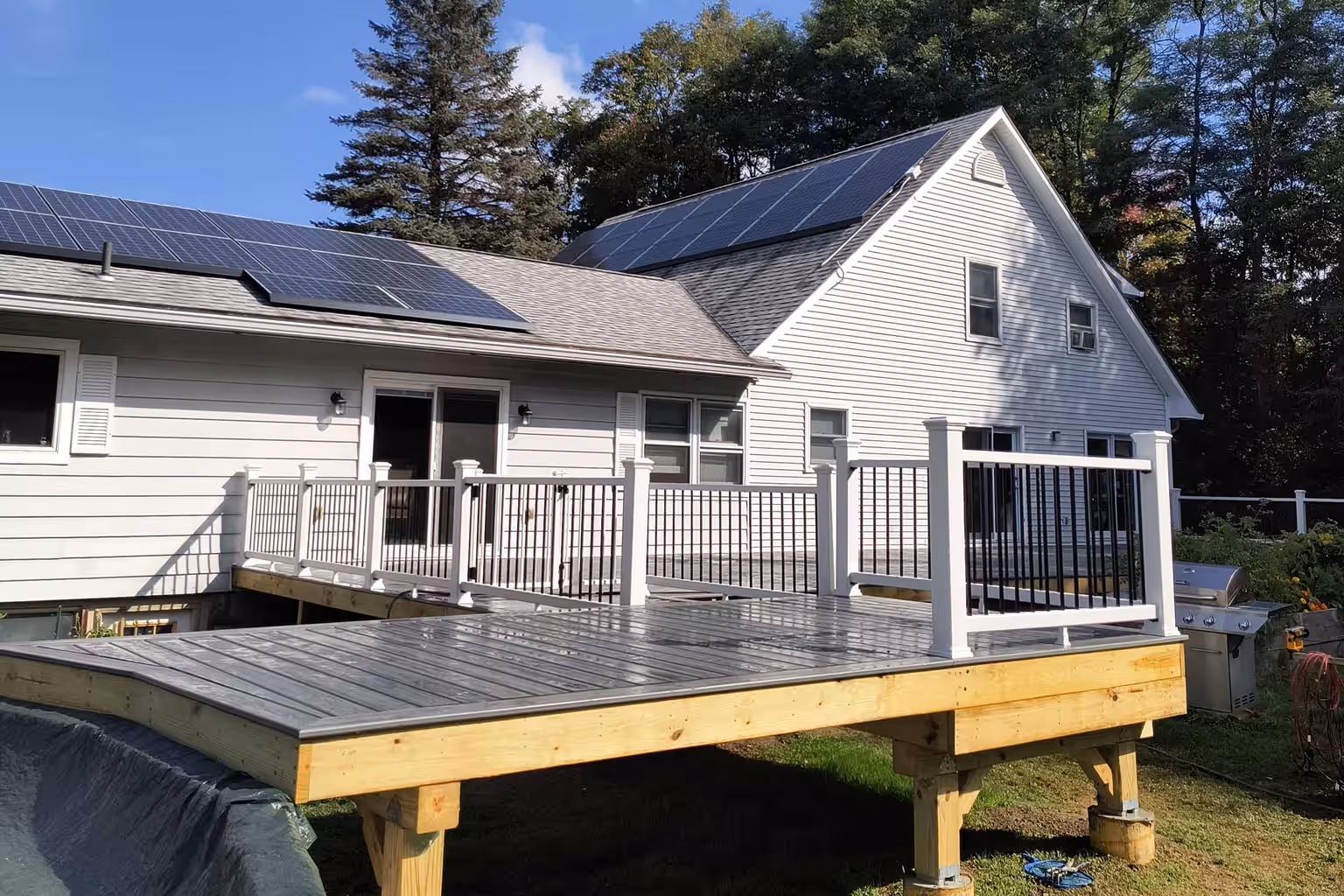 Newly built multi-level pressure-treated deck with railing and stairs at a Vermont home by Empirical Renovations