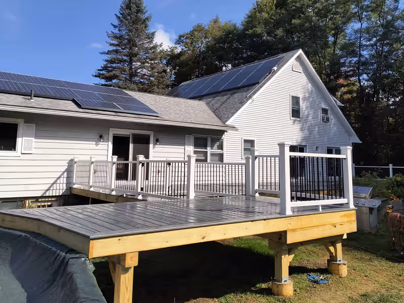 Raised composite deck with white railing and black balusters built by Empirical Renovations in Vermont