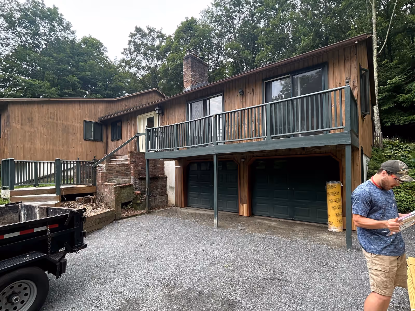 Aging deck with dark green railings and narrow side steps across the front of an Essex VT home, before rebuilding