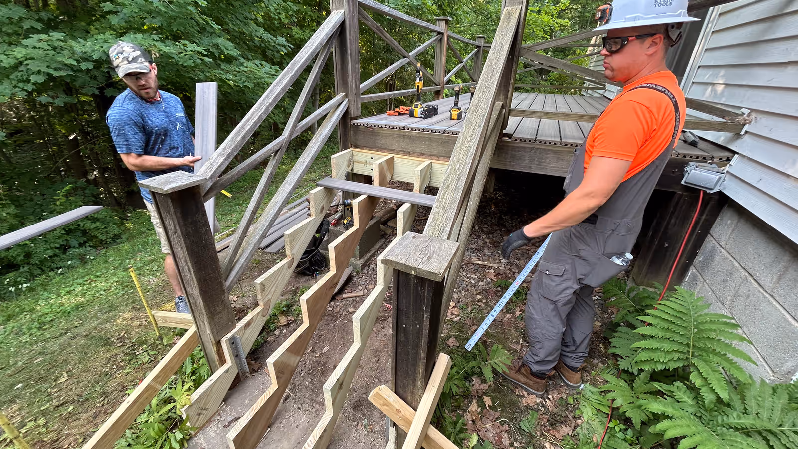 Empirical Renovations crew rebuilding deck stairs with new pressure-treated stringers on a weathered Vermont deck