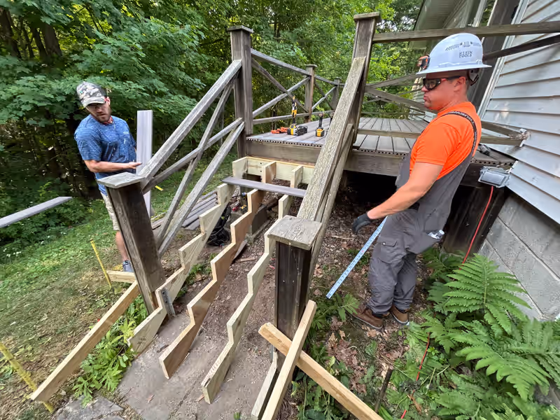 Empirical Renovations crew rebuilding deck stairs with new pressure-treated stringers on a weathered Vermont deck