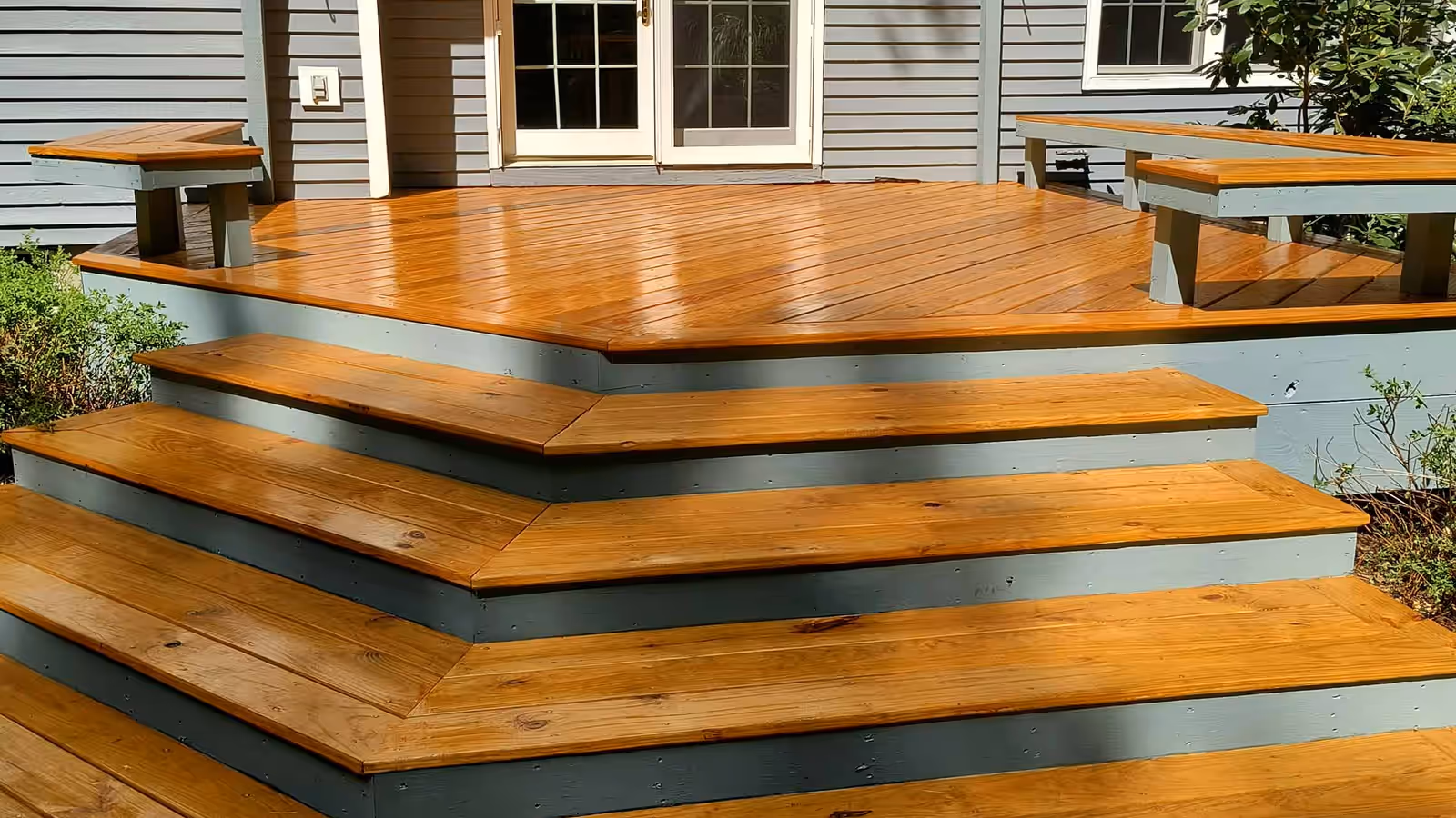 The same deck and wraparound steps after staining by Empirical Renovations, finished in a warm amber semi-transparent stain