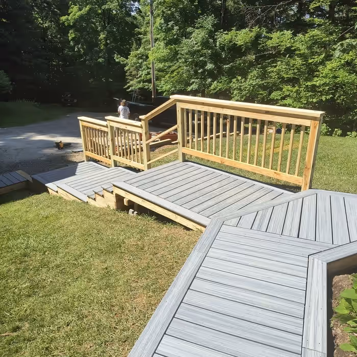 The same walkway rebuilt by Empirical Renovations in grey composite decking, with a new landing, steps and pressure-treated railings