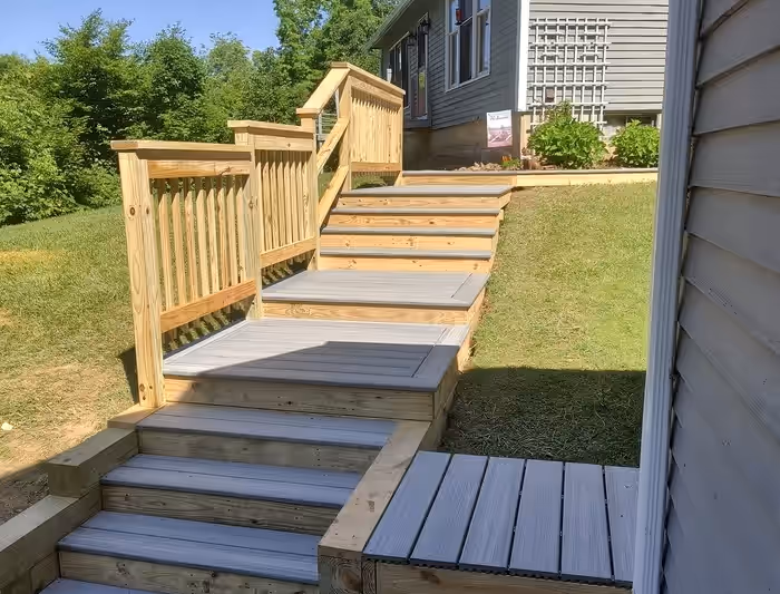 Composite deck walkway with pressure-treated stairs and railings connecting a Vermont home to the yard, built by Empirical Renovations