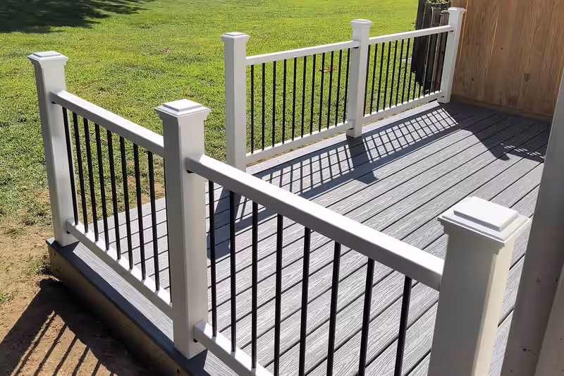 Low freestanding deck in grey composite with white railing and black balusters, built by Empirical Renovations in Vermont