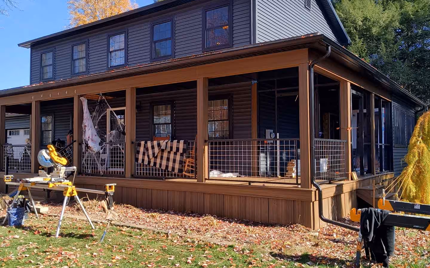 Full-width covered farmers porch with wire mesh railing built by Empirical Renovations on a Vermont home