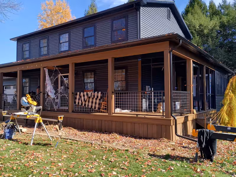 Full-width covered farmers porch with wire mesh railing built by Empirical Renovations on a Vermont home