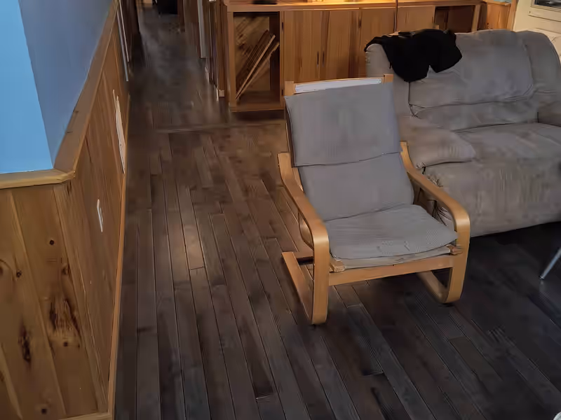 Dark stained hardwood flooring run through a living room and hallway by Empirical Renovations in Vermont