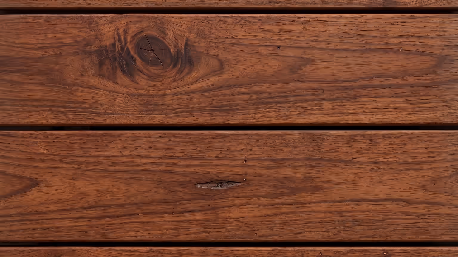 Deep red-brown mahogany hardwood deck boards with dense swirling grain around the knots