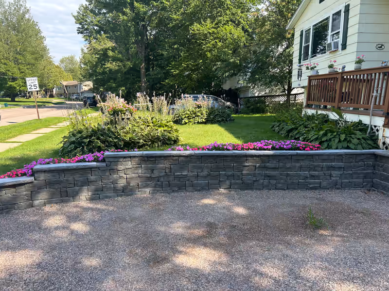 Segmental block retaining wall with capstones and a planted bed above, built by Empirical Renovations in Vermont