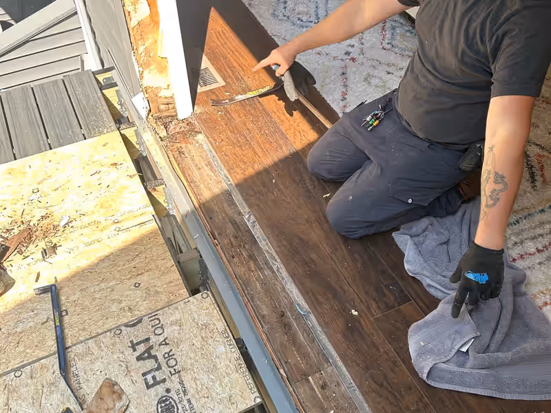 Empirical Renovations carpenter exposing rotted subfloor and framing at a doorway during a water damage repair in Vermont